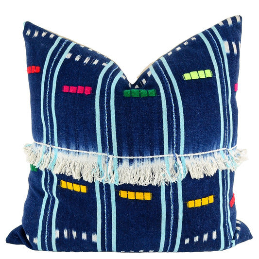 Front of pillow with blue patterns, colorful embroidery and white fringe made from vintage handwoven Baoulé/Baule cotton cloth from Africa's Ivory Coast, reflecting the traditions, symbols, and tribal lives of the Baoulé/Baule people