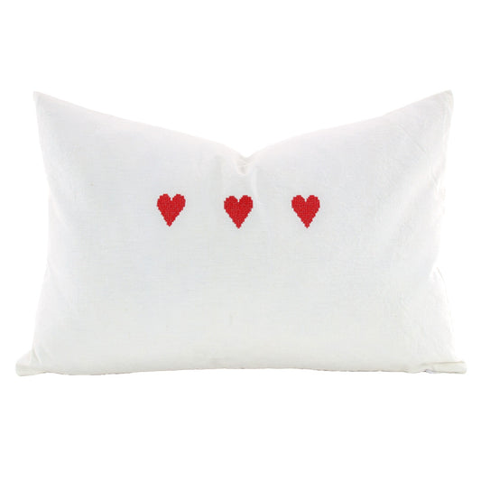 Front of pillow made from vintage European white linen and embroidered with three red hearts