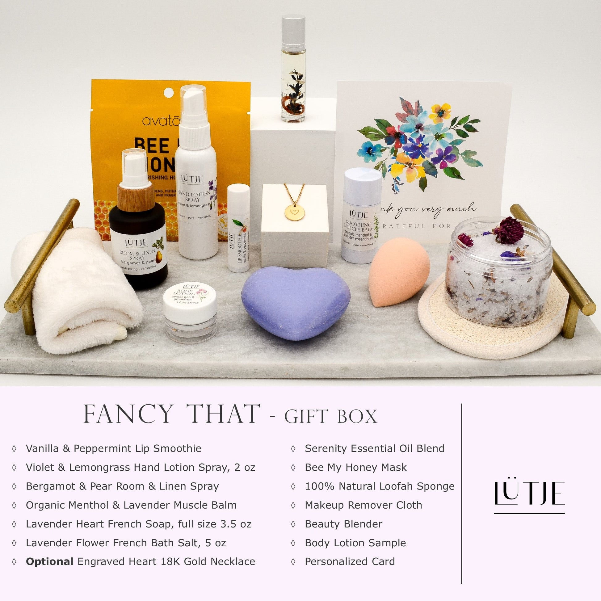 Fancy That Gift Box for women, BFF, wife, daughter, sister, mom, or grandma, includes Violet & Lemongrass hand lotion spray, essential oil, lip balm, soothing muscle balm, Bergamot & Pear room & linen spray, French soap, French bath salts, hydrating face mask, other bath, spa and self-care items, and optional 18K gold-plated necklace with engraved heart.